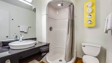A bathroom with a shower, toilet, sink, and a mirror.