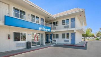 A two-story motel with a 'Welcome' sign, a visible office, and a parking lot.