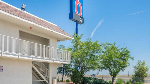 A motel with a balcony and a sign indicating it is number 6. - Elegant Queen Bed|Pool|Free Parking (Williams)