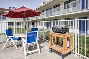 An outdoor patio with a table and chairs, a barbecue grill on a cart, and a red umbrella. - Elegant Queen Bed|Pool|Free Parking (Williams)