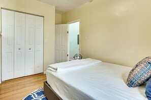 A bedroom with a bed, a wardrobe, and a door leading to another room. - Walk to HBLR & Liberty State Park: Jersey City Apt (Jersey City)