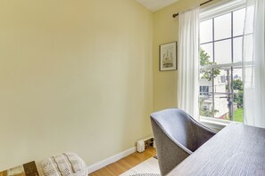 A room with a window, a framed picture on the wall, and a grey chair. - Walk to HBLR & Liberty State Park: Jersey City Apt (Jersey City)