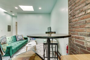 A room with a green sofa, a round table, and a brick wall. - Walk to HBLR & Liberty State Park: Jersey City Apt (Jersey City)