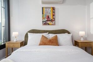 A hotel room with a bed, two bedside tables, a window, and a wall-mounted painting. - River-view balcony, free parking (Docklands)