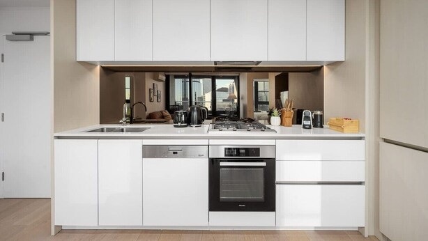 Une cuisine moderne dotée d’un îlot central, d’appareils électroménagers intégrés et offrant une vue sur la ville.