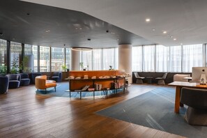 Een moderne zithoek met een bank, fauteuils, een tafel en een laptop.