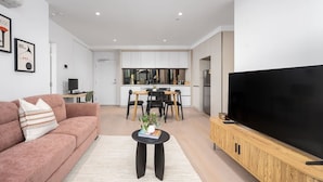 Un salon moderne avec un canapé, une table basse et un téléviseur posé sur un meuble en bois.