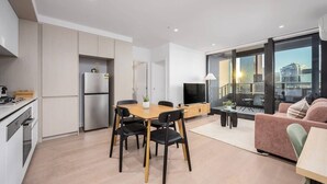 Un appartement moderne doté d’une cuisine, d’un coin repas et d’un balcon offrant une vue sur la ville.