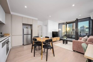 A modern apartment with a kitchen, dining area, and a balcony with a city view. - River-view balcony, free parking (Docklands)