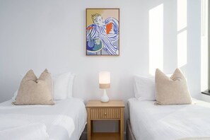 A hotel room with two beds, a nightstand with a lamp, and a painting on the wall. - River-view balcony, free parking (Docklands)