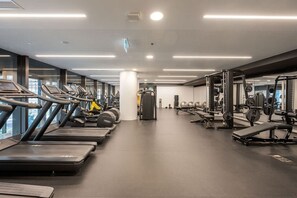 Een fitnessruimte met loopbanden, krachtapparaten en fitnessballen.