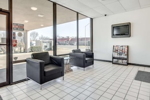 A hotel lobby with large windows, two armchairs, a coffee table, a television, and a magazine rack. - 1 Queen Bed | Smoking, Kitchen, Sofa-Bed (Longview)
