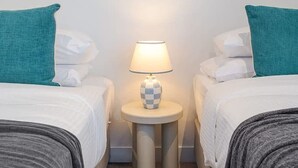 Ein Hotelzimmer mit zwei Betten, einem Nachttisch mit Lampe und einem gerahmten Kunstwerk an der Wand.