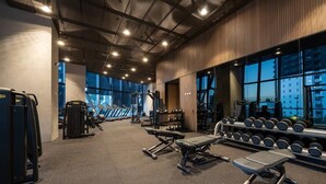 Ein Fitnessstudio mit Laufbändern, Kraftgeräten und Kurzhanteln.