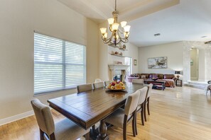 Un'ampia sala da pranzo con un grande tavolo in legno, diverse sedie e un lampadario.