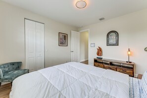 A bedroom with a large bed, a dresser, a chair, and two doors.