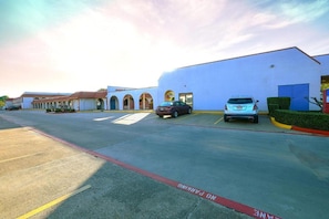 A parking lot with a building featuring arched windows and a flat roof. - 1 King Bed | Non-Smoking, Kitchen, Sofa (Longview)