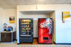 A vending machine area with a Pepsi machine and a Coca-Cola machine, a small cabinet with a cash register, and a sign on the wall. - 1 King Bed | Non-Smoking, Kitchen, Sofa (Longview)