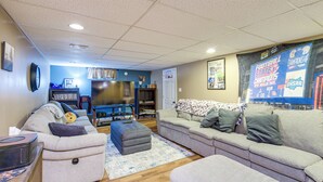 A living room with a large flat-screen TV, a sofa, a coffee table, and a rug. - Hot Tub, Gym & Office! Family Home in Massillon (Massillon)