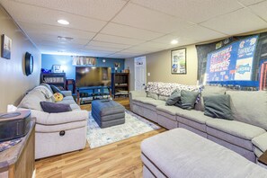 A living room with a large flat-screen TV, a sofa, a coffee table, and a rug. - Hot Tub, Gym & Office! Family Home in Massillon (Massillon)