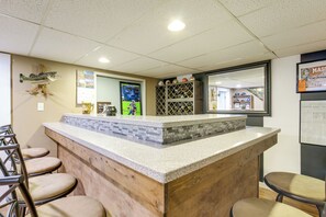 A bar area with a counter, seating, and a display of sports memorabilia. - Hot Tub, Gym & Office! Family Home in Massillon (Massillon)