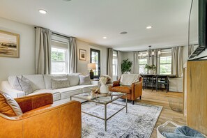 A modern living room with a sofa, coffee table, and a dining area with chairs and a table. - Modern Farmhouse Between Mount Snow & Stratton! (Wardsboro)