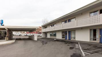 A parking lot with a building featuring a patterned facade and a covered entrance.