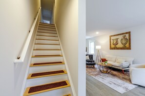 A staircase with wooden steps and white walls, leading to a room with a white sofa, a coffee table, and a painting on the wall. - Hickory Townhome w/ Balcony: 2 Mi to Downtown (Hickory)