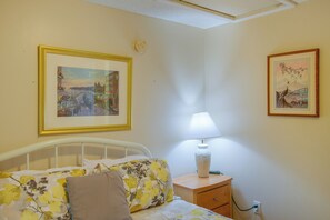 A bedroom with a bed, a nightstand with a lamp, and two framed pictures on the wall. - Walk to Beach! Water-View Fairhope Retreat (Fairhope)