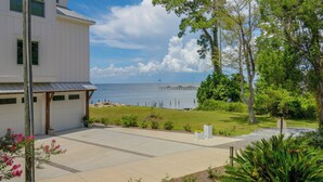 Ein zweistöckiges Haus mit Garage, einem gepflasterten Einfahrt und Blick auf das Meer mit einem Pier im Hintergrund.