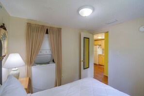 Une chambre d’hôtel avec un lit, une machine à laver, un miroir et une lampe.