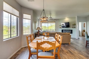 A dining area with a wooden table and chairs, a sofa, and a television in the background. - Pool & Hot Tub Access! Family Condo in Oro Valley (Oro Valley)
