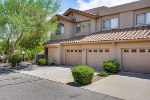 A two-story residential building with a tiled roof, multiple garage doors, and a landscaped front yard with small bushes and a tree. - Pool & Hot Tub Access! Family Condo in Oro Valley (Oro Valley)