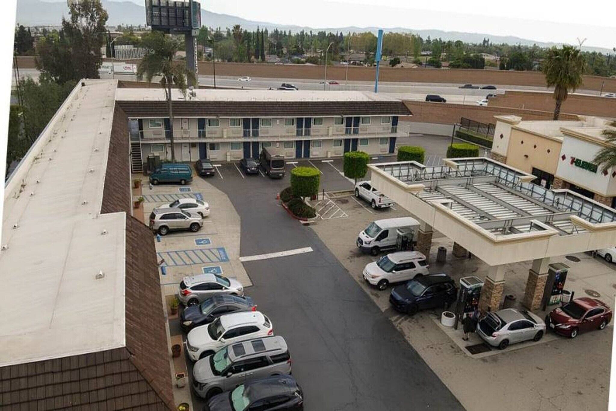 Un estacionamiento con varios autos, un edificio de techo plano y cielo despejado.