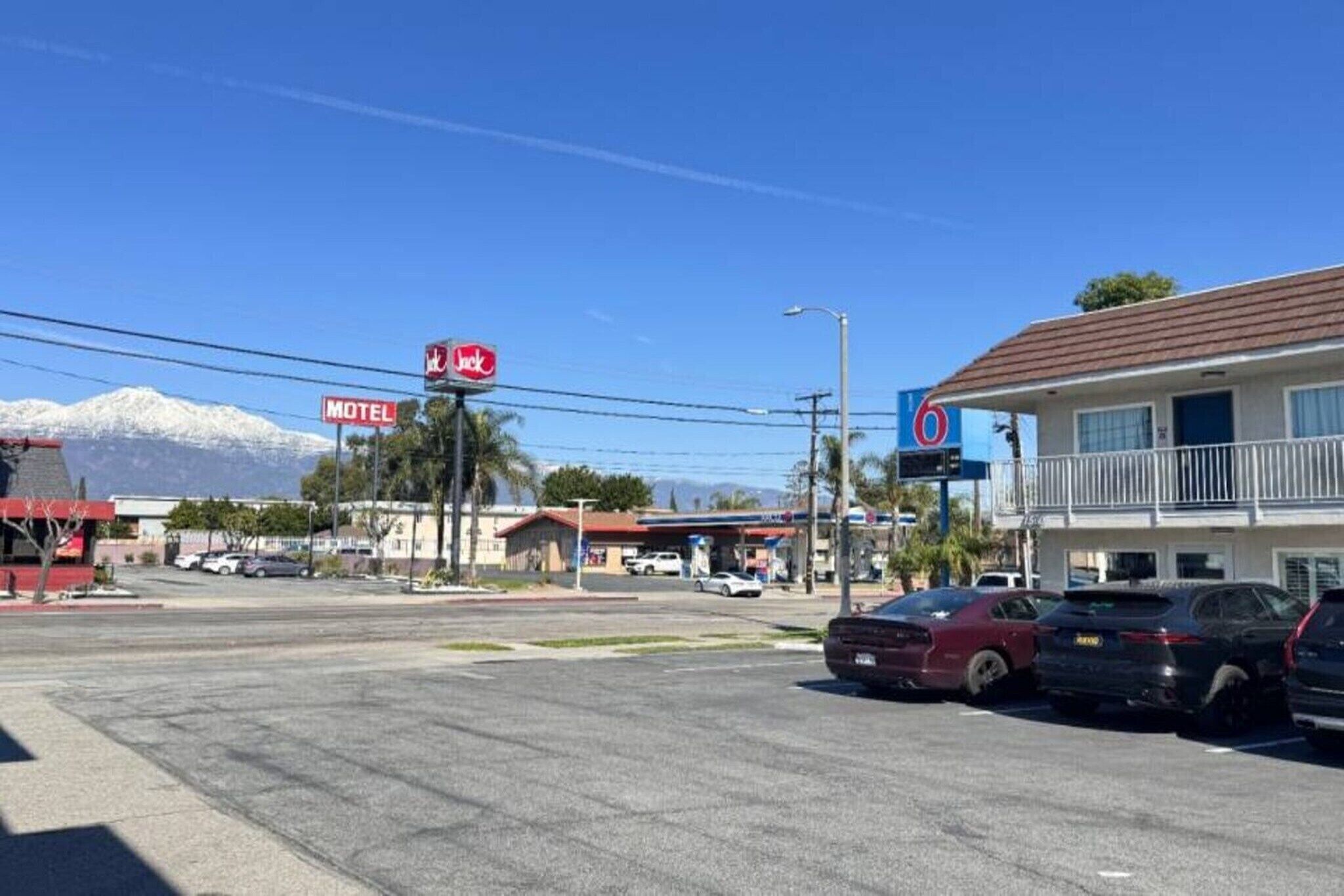A motel with a sign, a building with a balcony, and a mountain in the background.
