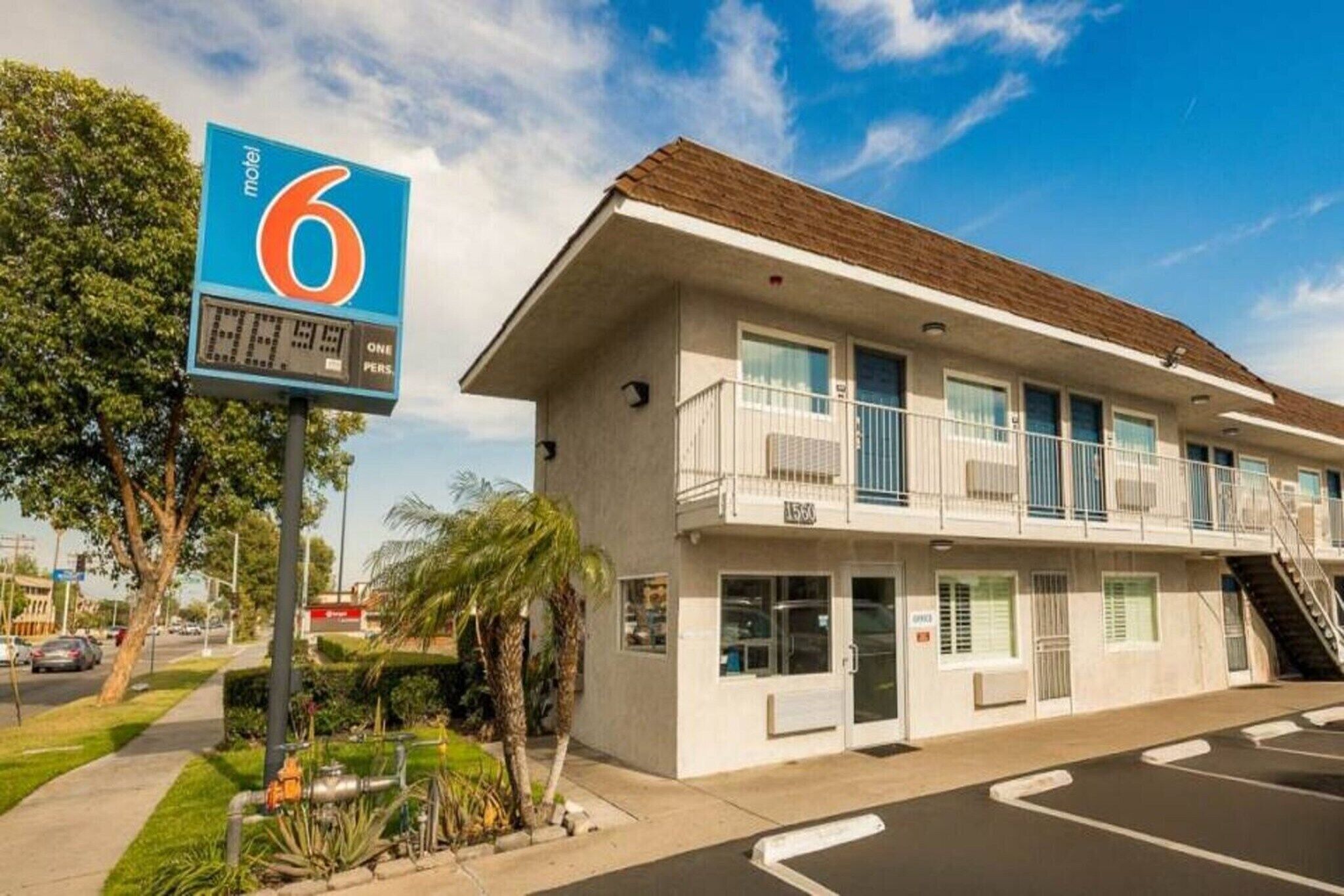 A motel with a sign indicating 6 rooms, a two-story building with a flat roof, and a parking lot.