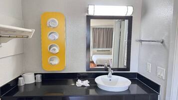 A bathroom with a black countertop, a white sink, a mirror, and a yellow towel rack with four towels.