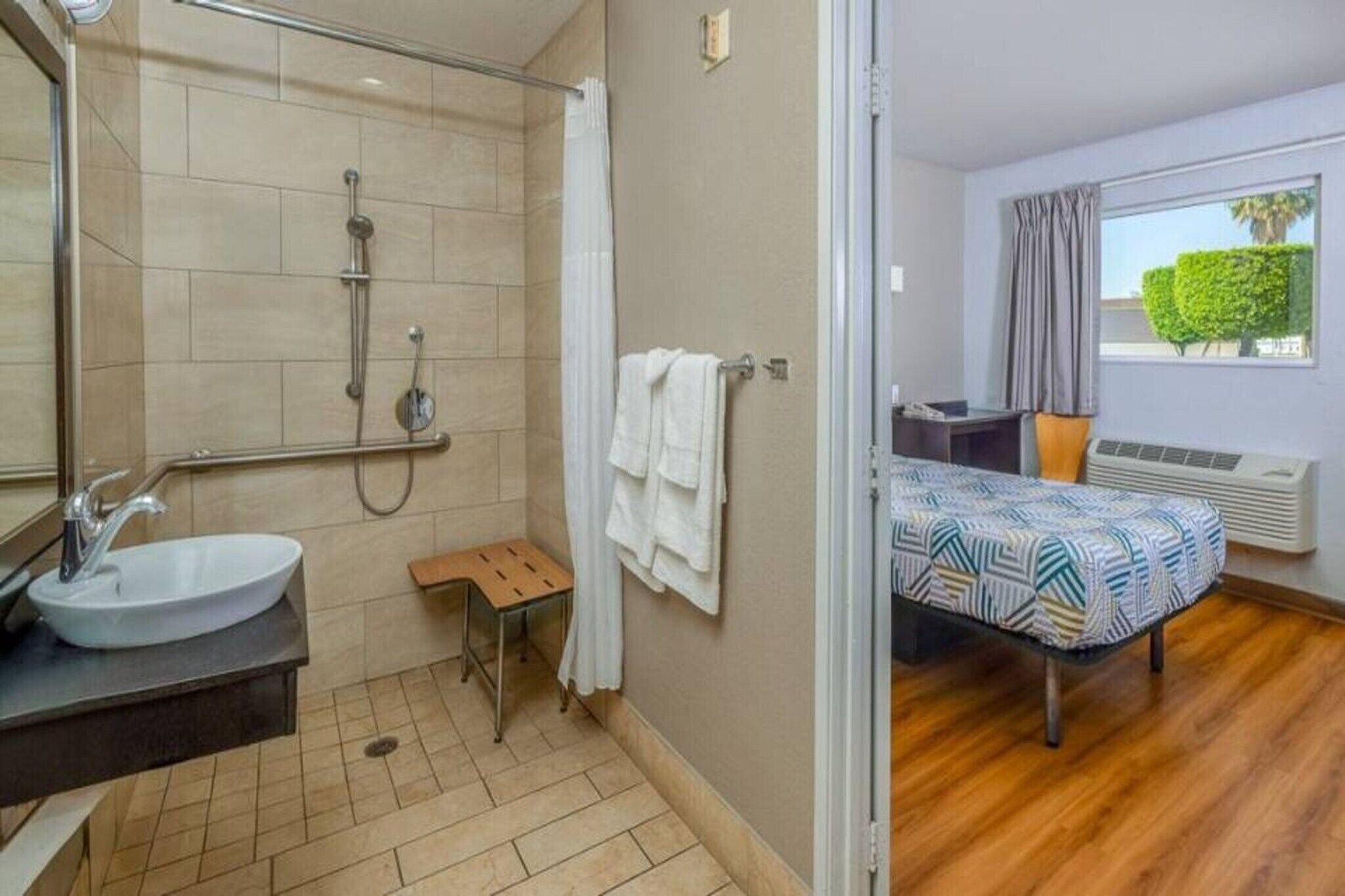 A bathroom with a sink, shower, and a small stool.