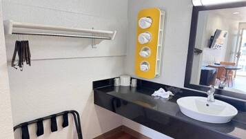 A bathroom with a black countertop, a white sink, a mirror, and a towel rack.