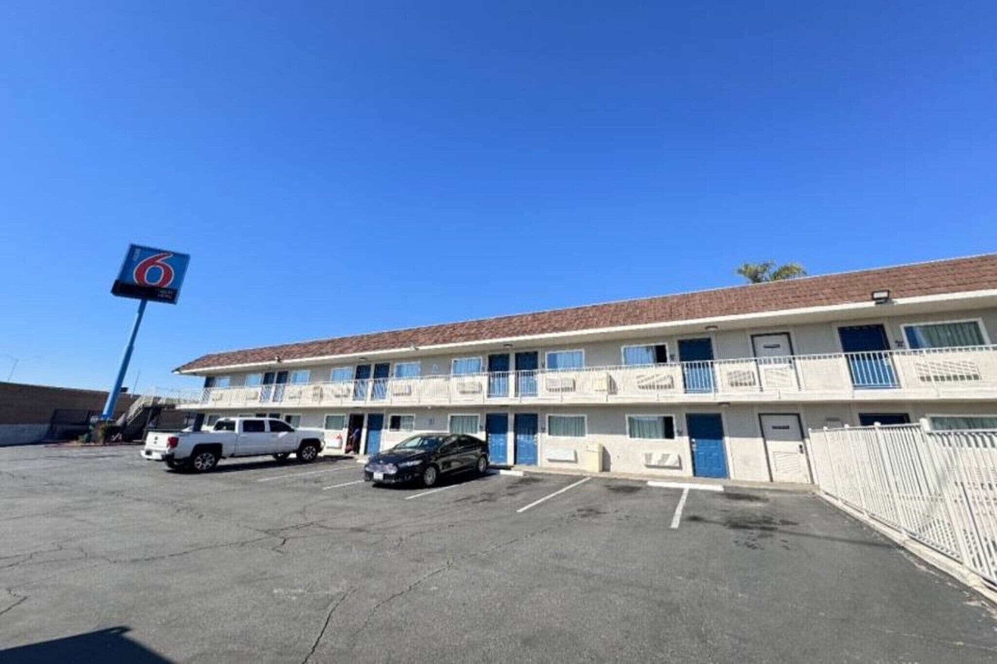 A motel with a parking lot, a white pickup truck, and a black car parked in front.