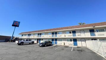 A motel with a parking lot, a white pickup truck, and a black car parked in front.