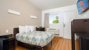 A hotel room with a bed, a desk, a TV, and a window with a view.