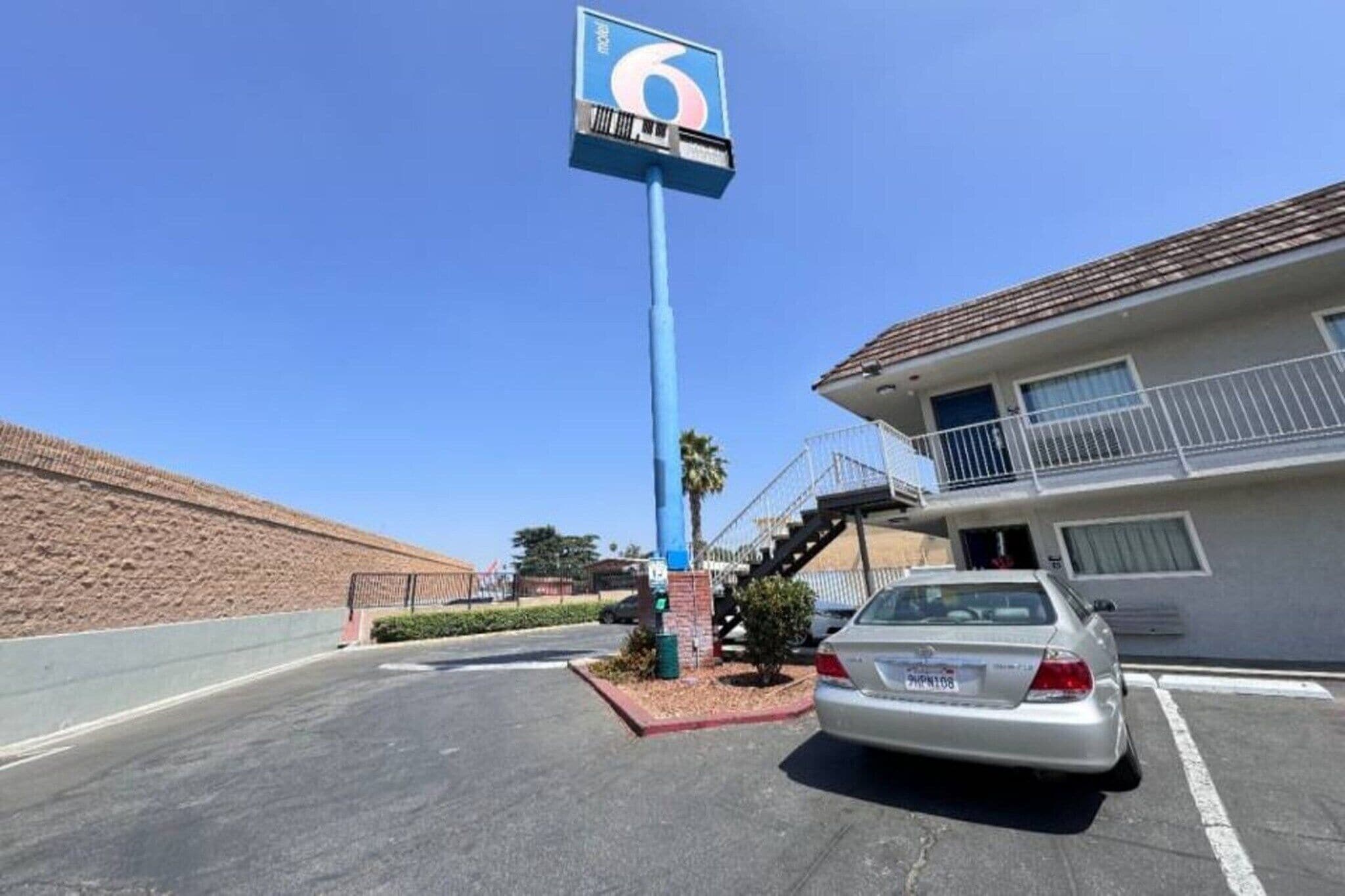 A parking lot with a building that has a balcony and a sign with a number.