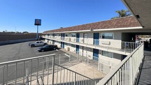 A motel with a parking lot, a sign indicating the number 6, and a building with a flat roof.