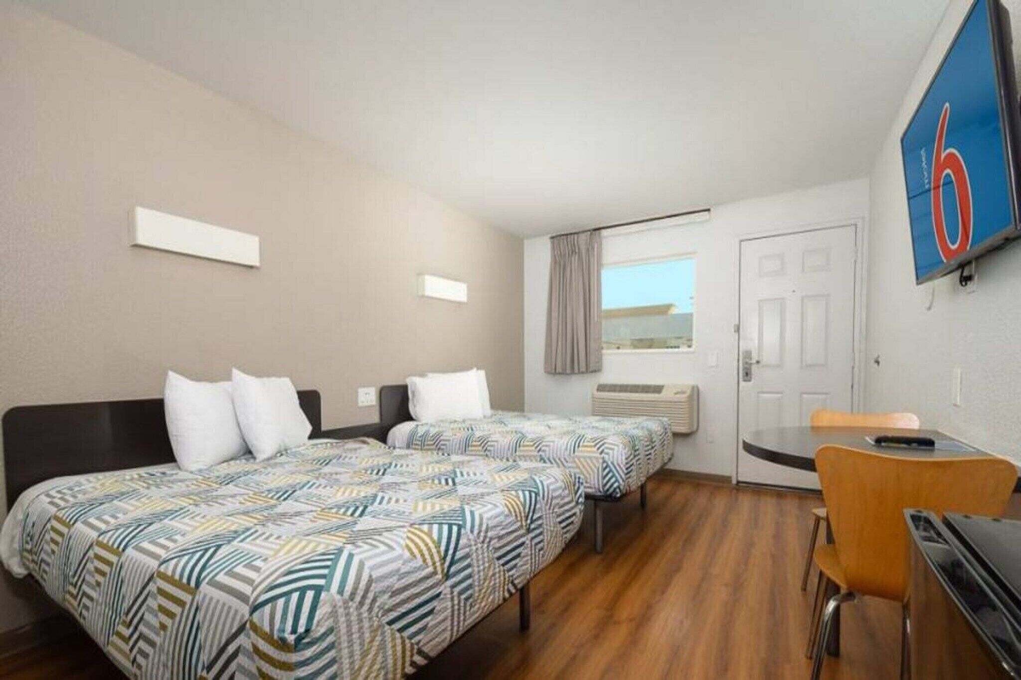 A hotel room with two beds, a desk, and a chair.