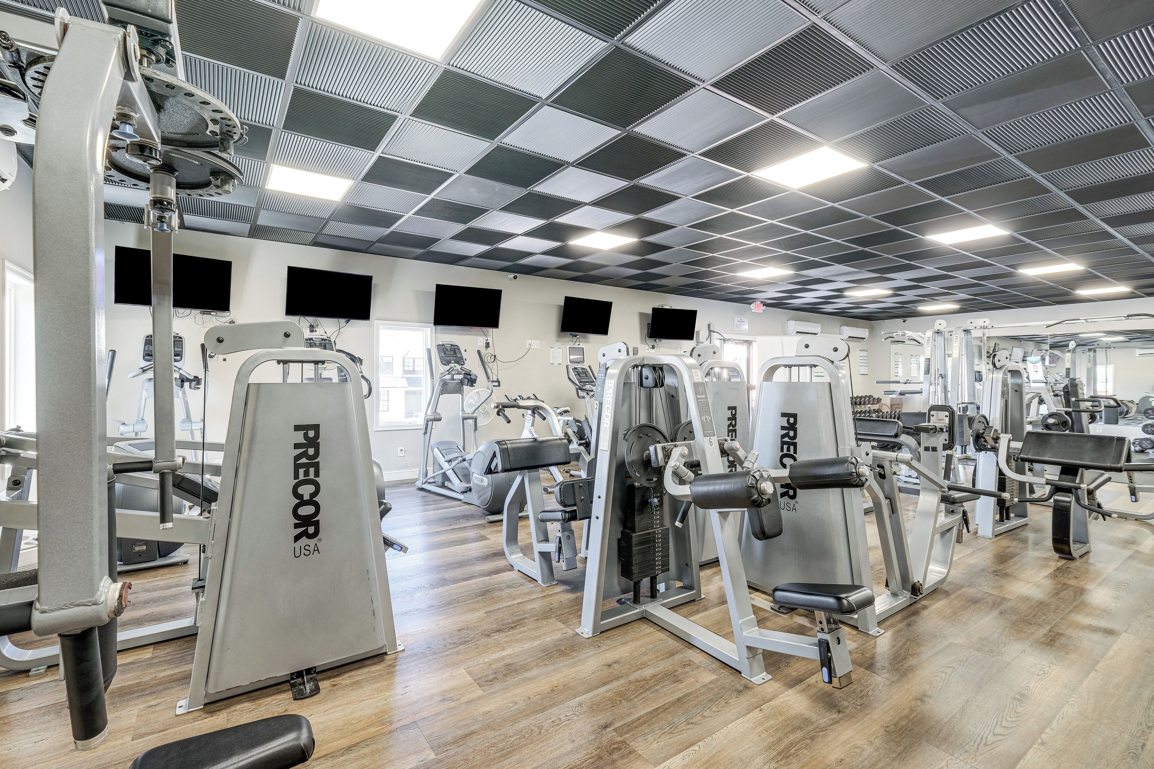 Une salle de sport équipée de divers appareils d’exercice, notamment des bancs de musculation et des appareils de cardio.
