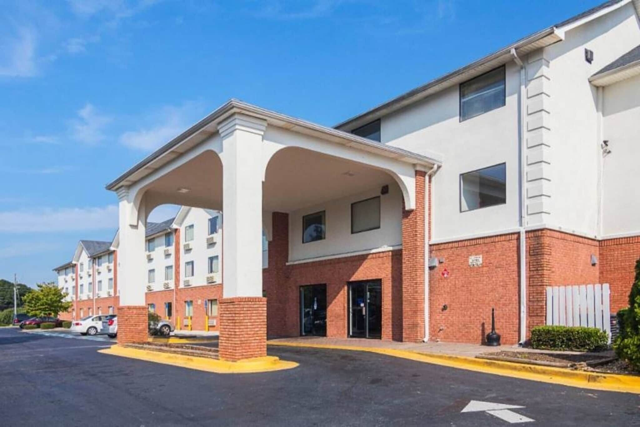 Un hôtel à plusieurs étages doté d’une entrée couverte et d’un parking.