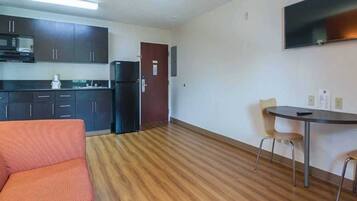 Um espaço compacto com cozinha americana, área de jantar com mesa e cadeiras, e um sofá.