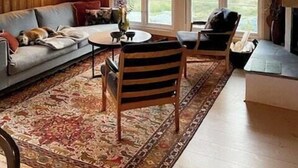 A cozy living room with a sofa, a coffee table, and a rug. There are large windows and a fireplace. - Secluded cabin with views of Raulandsfjell (Rauland)