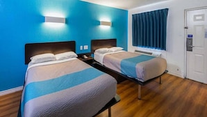 A hotel room with two beds, a blue wall, a window with curtains, and a door. - 2 FULL BEDS | NON-SMOKING (Grand Prairie)